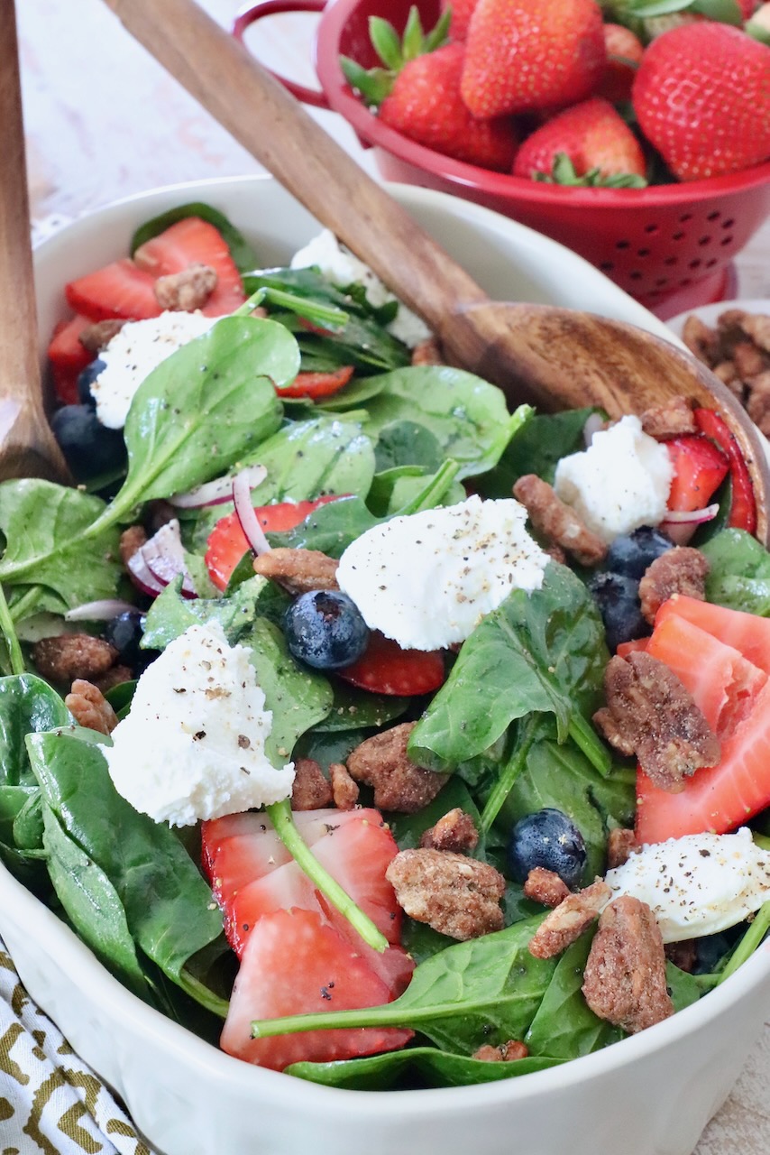 salad in large serving bowl topped with ricotta cheese, pecans and strawberries