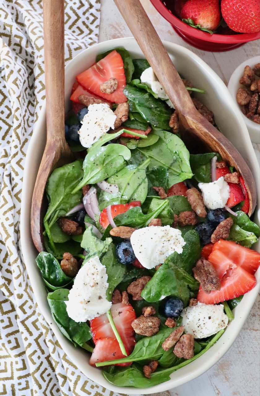 large salad in serving bowl topped with dollops of ricotta cheese and sliced strawberries