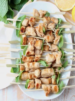 Overhead shot of chicken skewers on white plate