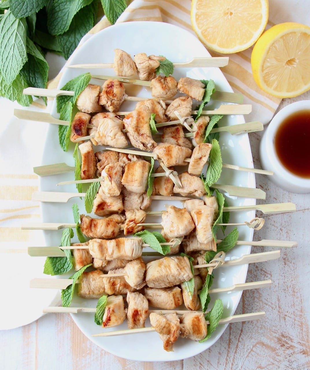 Grilled bourbon chicken on skewers with mint leaves