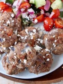Greek meatballs on plate with tomato cucumber salad