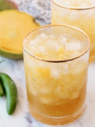 margaritas in glasses next to fresh sliced mango