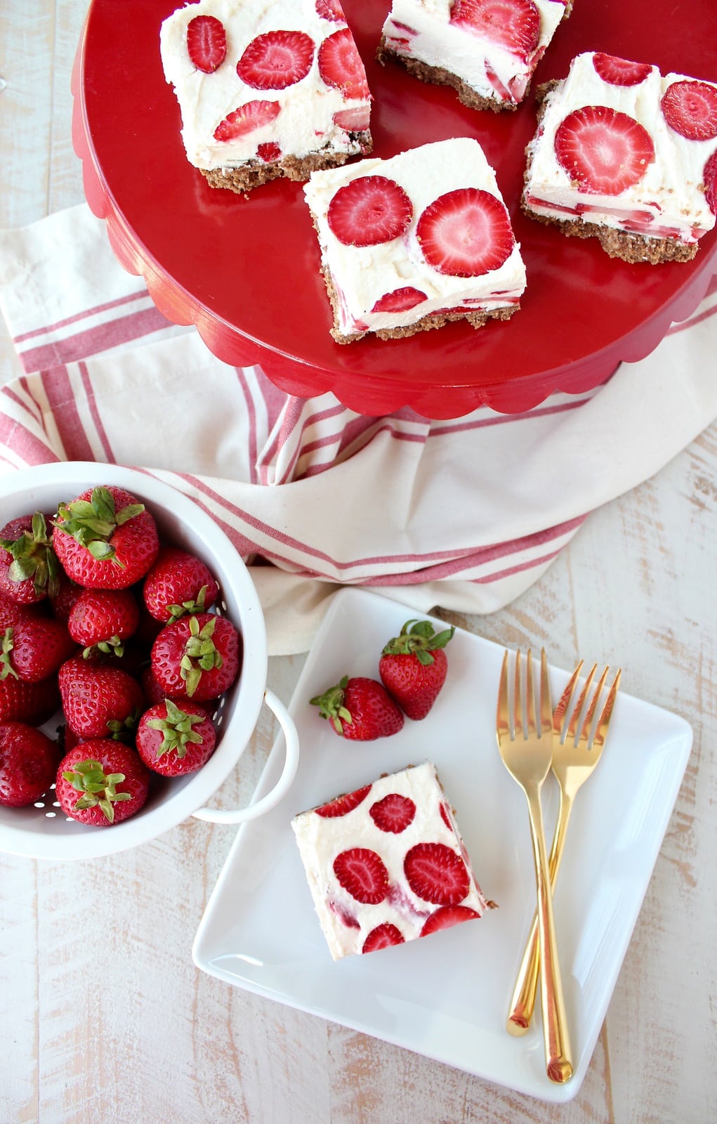 strawberry cheesecake bars on red serving tray and on white plate with gold forks