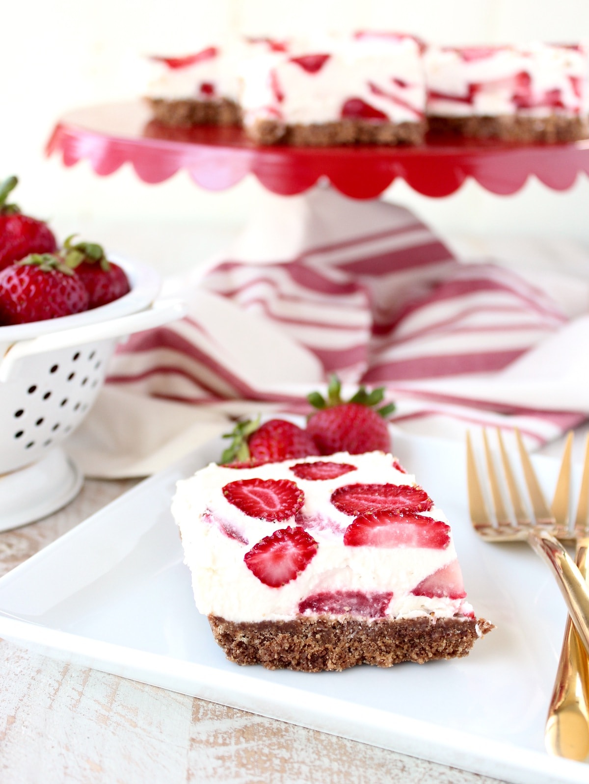 strawberry cheesecake bar on white plate with gold forks