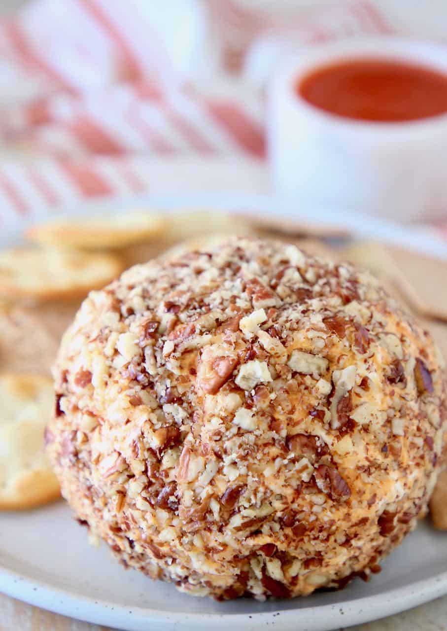 Buffalo cream cheese ball rolled in pecans on plate with crackers