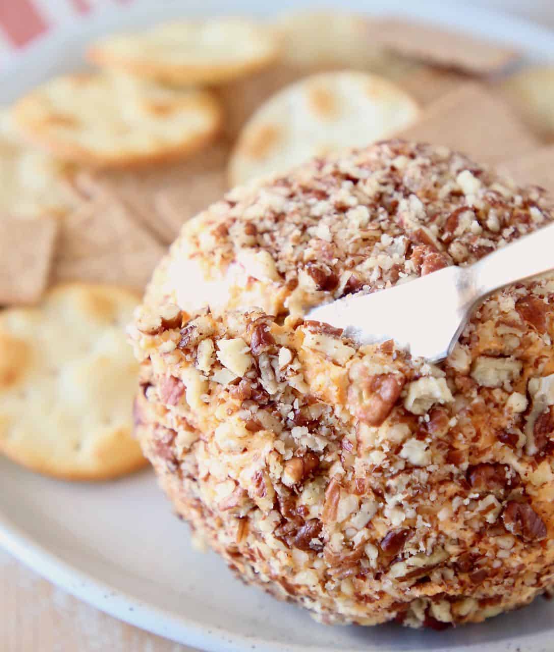 Buffalo cream cheese ball being sliced into with cheese knife