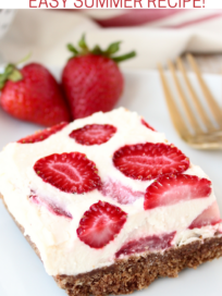 strawberry cheesecake bar on plate with gold fork and fresh strawberries
