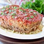 Italian Meatloaf sitting on large bowl of spaghetti noodles with fresh parsley on top
