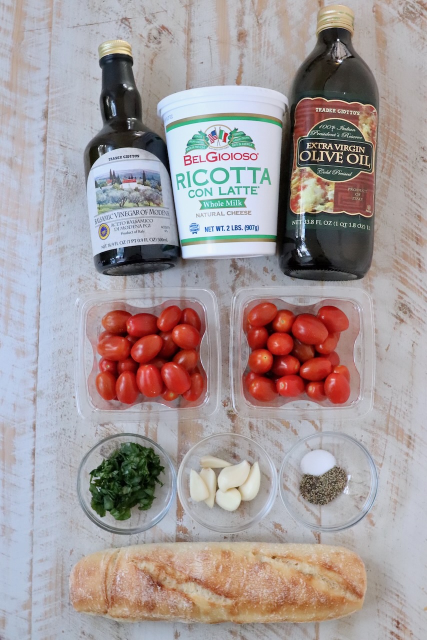 ingredients for tomato ricotta bruschetta on a white wood board