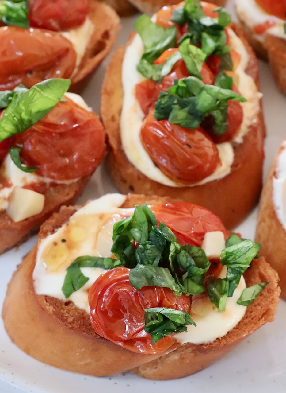 roasted tomatoes and basil on top of ricotta cheese on toast