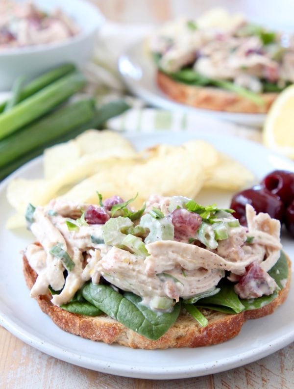 Chicken salad on toast with potato chips on white plate