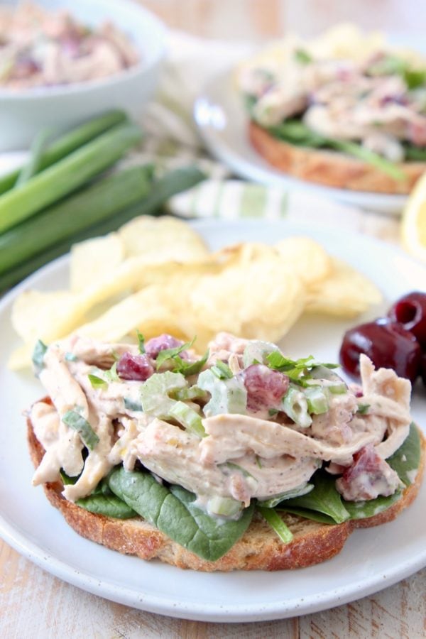 Chicken salad on toast on white plate with potato chips