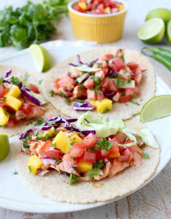 Chipotle honey glazed salmon is placed in warm corn tortillas & topped with fresh mango salsa in this mouth-watering recipe for healthy salmon tacos!