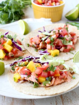 Chipotle honey glazed salmon is placed in warm corn tortillas & topped with fresh mango salsa in this mouth-watering recipe for healthy salmon tacos!