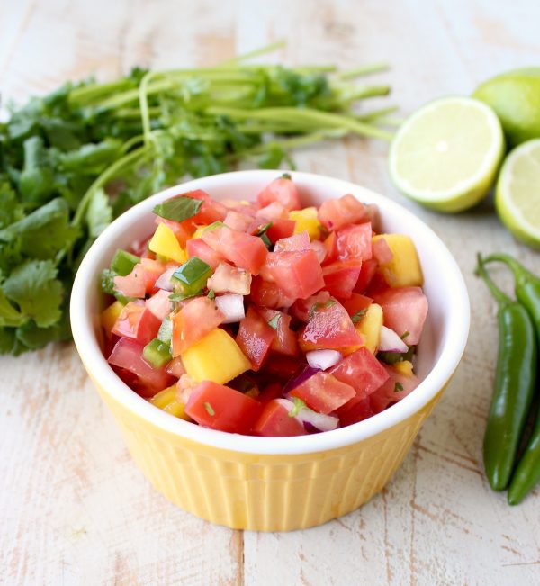 A yellow dish filled with diced tomatoes, jalapeños, mango, and onion. 