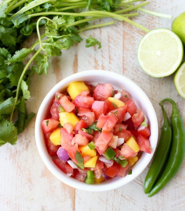  A yellow dish filled with diced tomatoes, jalapeños, mango, and onion. 