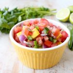 Toss this easy, homemade Tomato Mango Salsa recipe together in 5 minutes to serve on top of fresh fish, tacos or with chips for dipping!