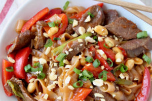Kung pao beef and noodles in large white bowl