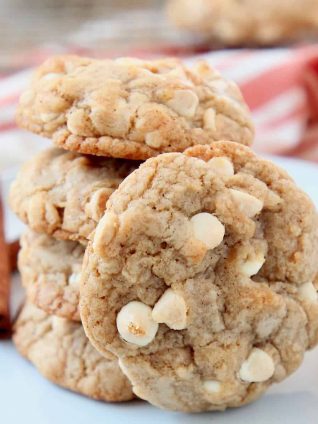 Pumpkin spice white chocolate chip cookies stacked up on a plate