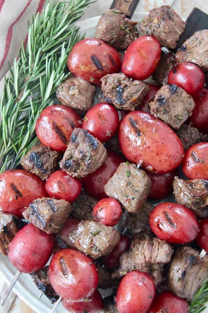 pieces of steak and baby potatoes on skewers stacked up on plate