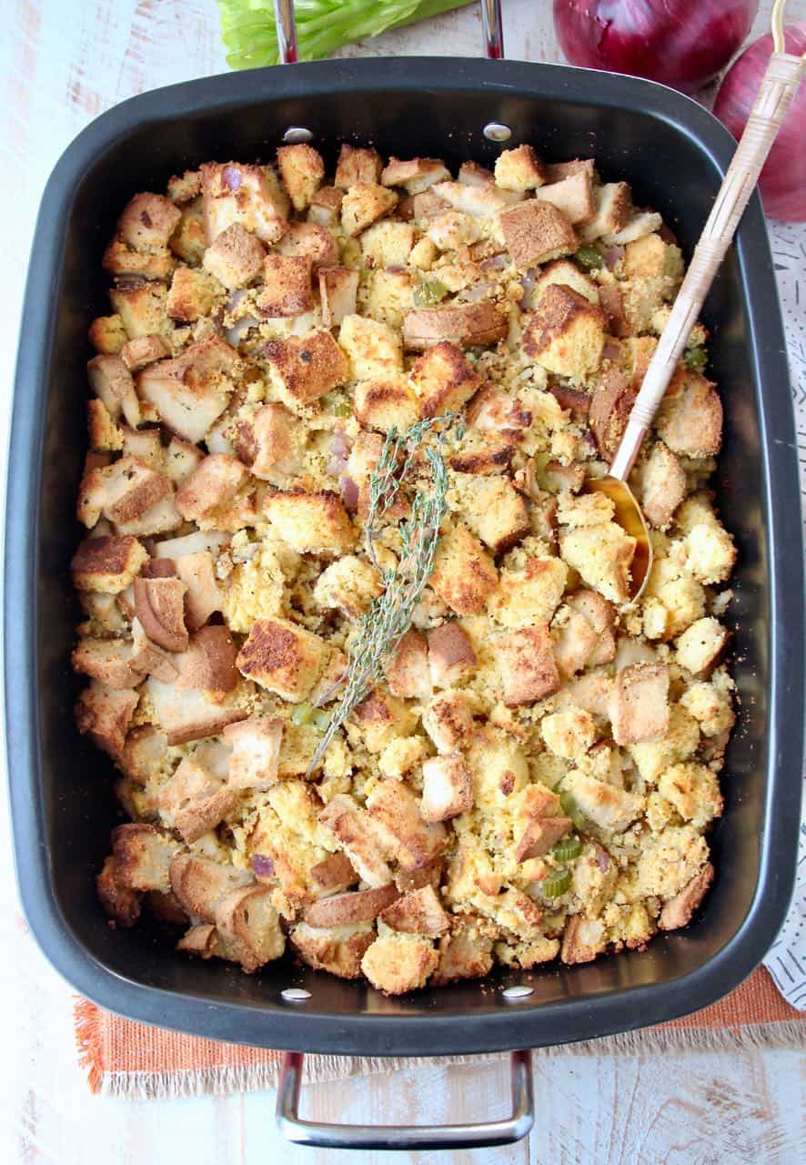 Gluten free cornbread stuffing in roasting pan with spoon and fresh thyme sprigs