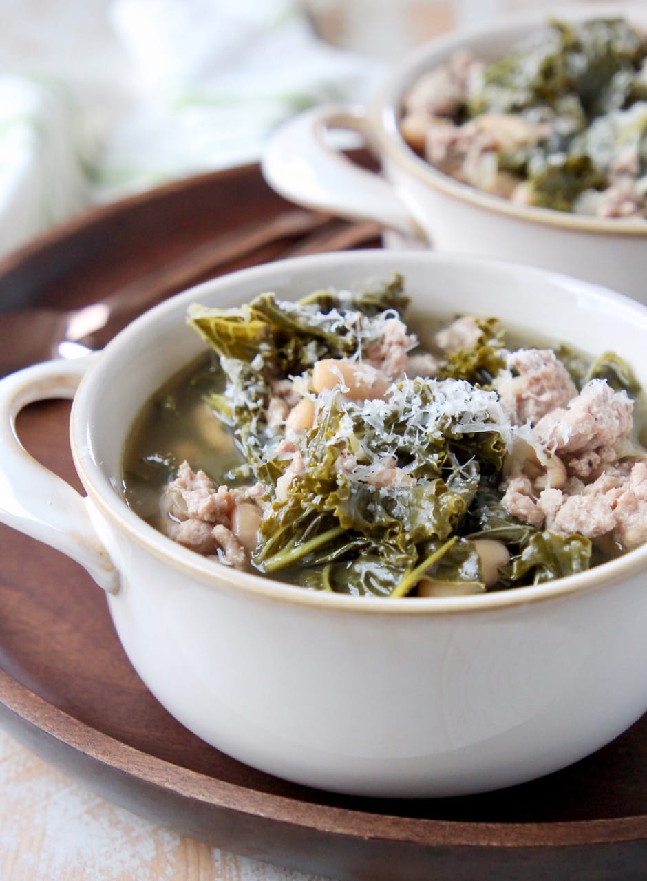 Ground turkey and kale soup in white soup crock on wood tray