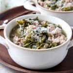 Kale turkey soup in white soup crock on dark wood tray