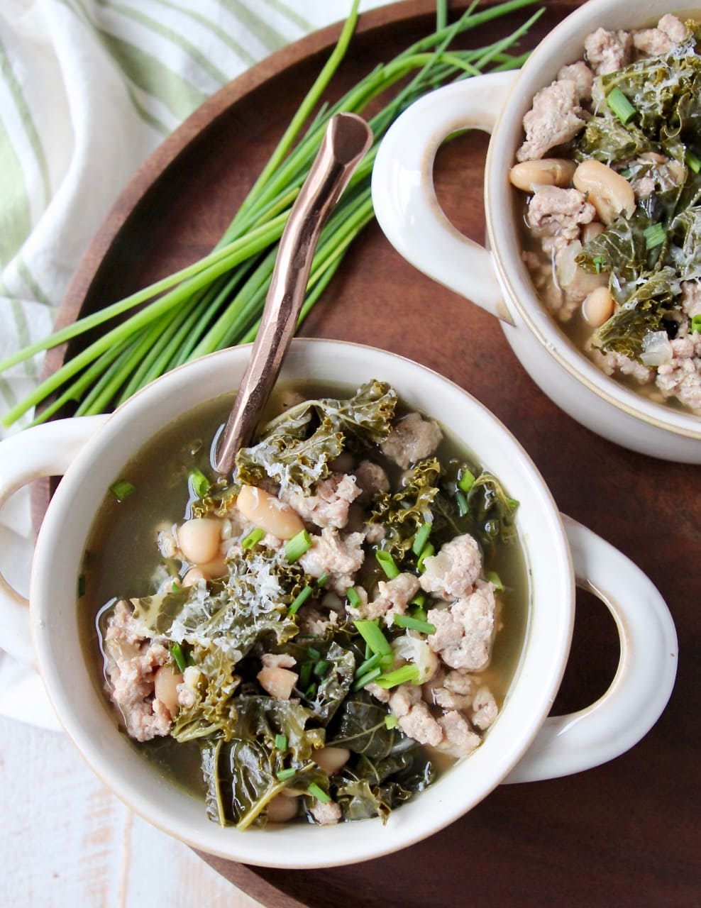 Kale Turkey Soup in white soup crocks on wood tray with fresh chives