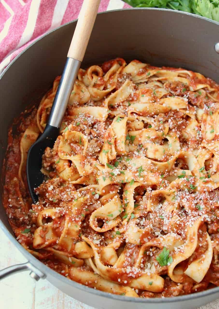 pasta tossed in tomato meat sauce in large pot with serving spoon