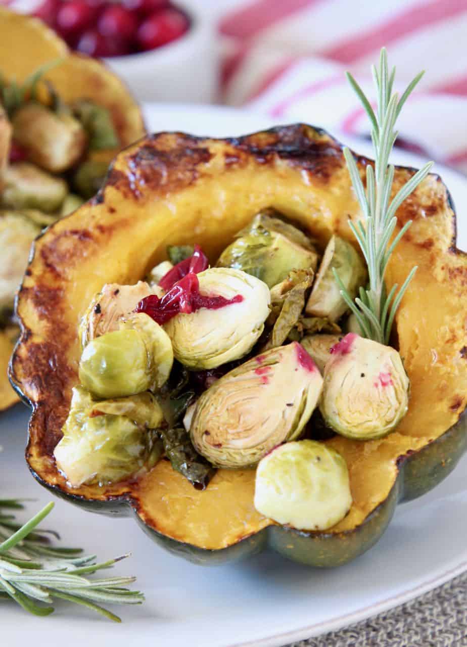 stuffed acorn squash half filled with roasted brussels sprouts and cranberries