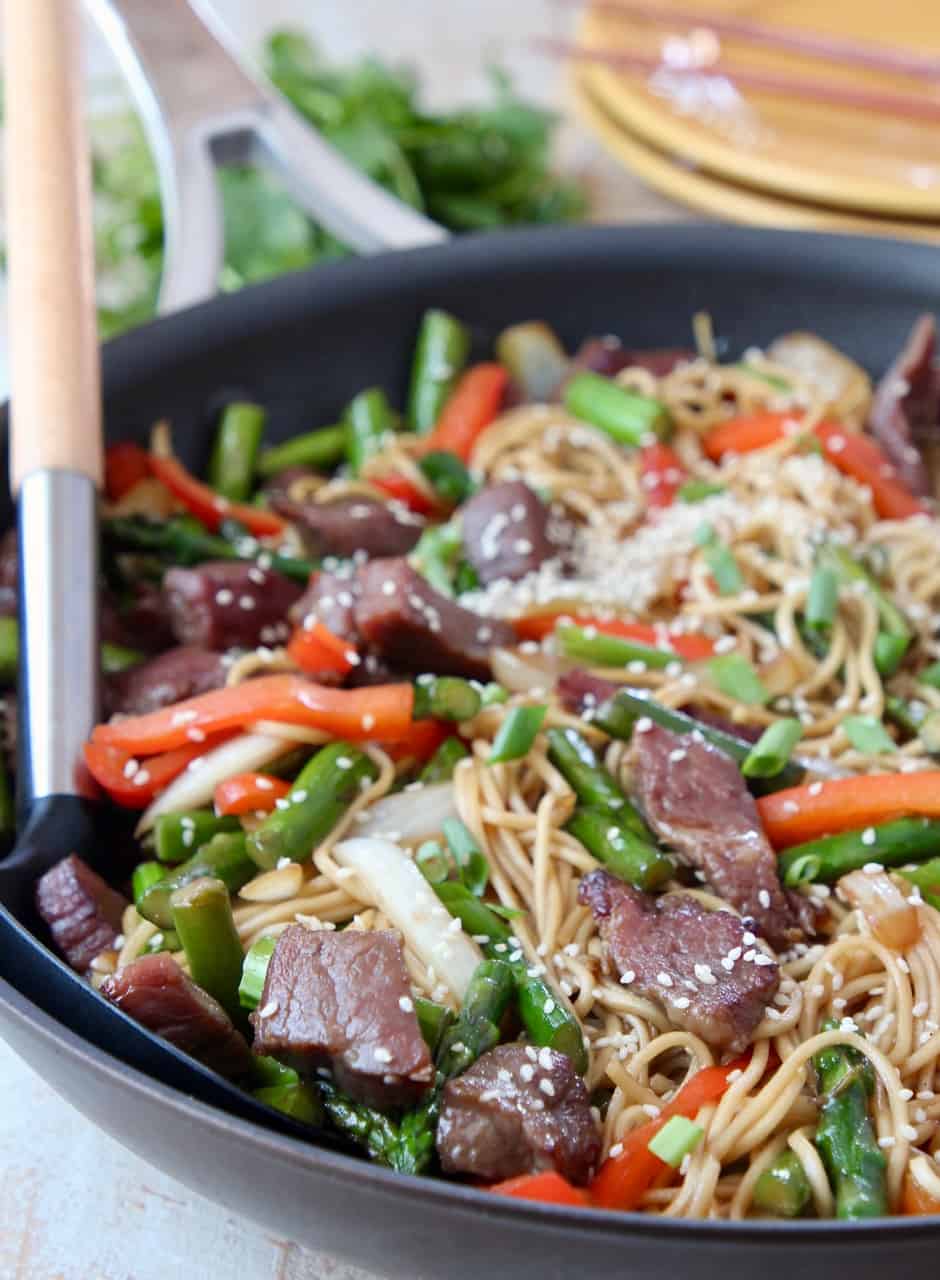 beef stir fry with noodles in skillet with serving spoon