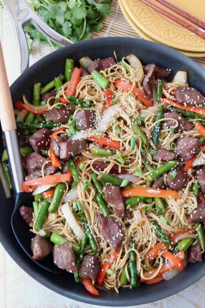 Overhead image of beef stir fry with noodles in skillet with spoon