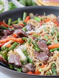 beef stir fry with noodles in skillet with spoon