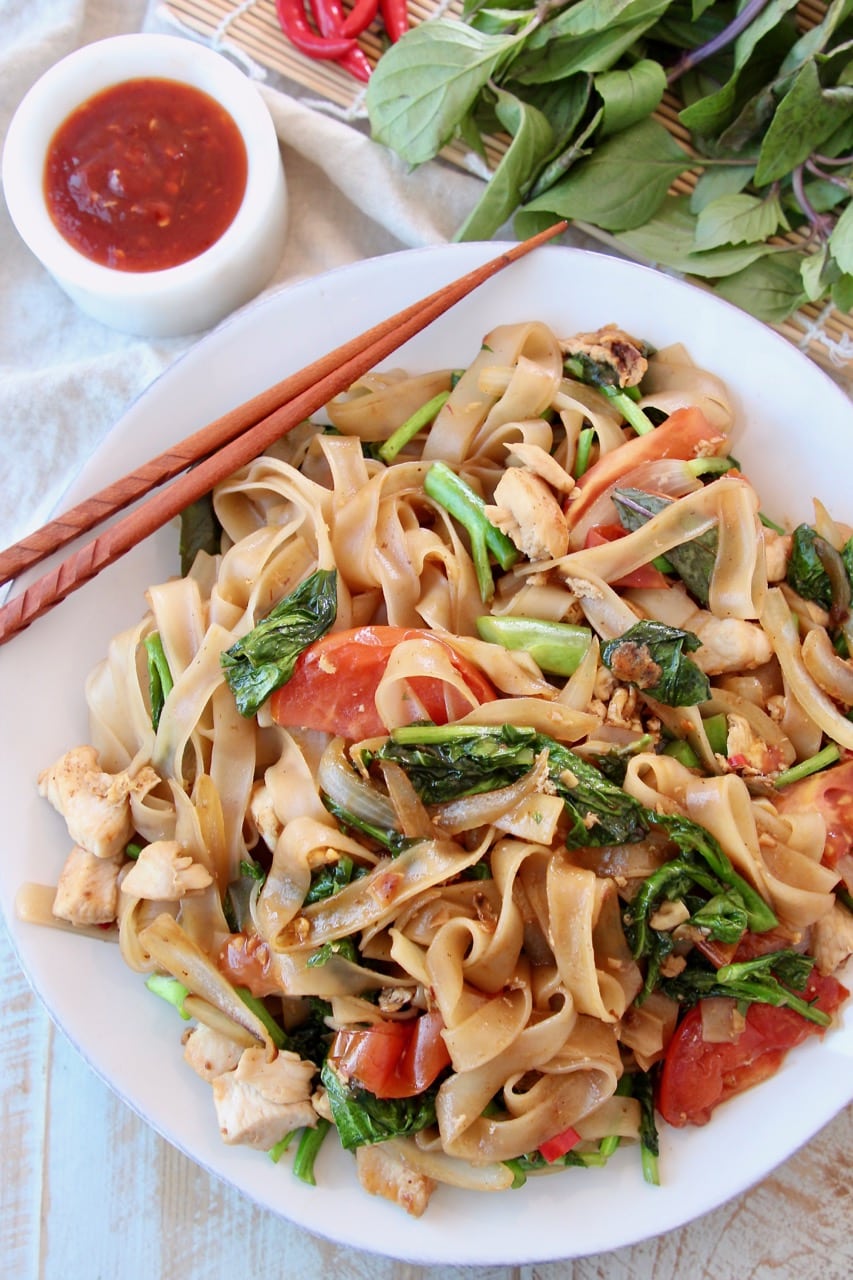 Overhead shot of Drunken Noodles on white plate with brown chopsticks on the side