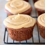 Chocolate cupcake with peanut butter frosting on black wire baking rack