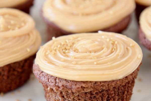 chocolate cupcakes on plate with peanut butter frosting and gold sprinkles