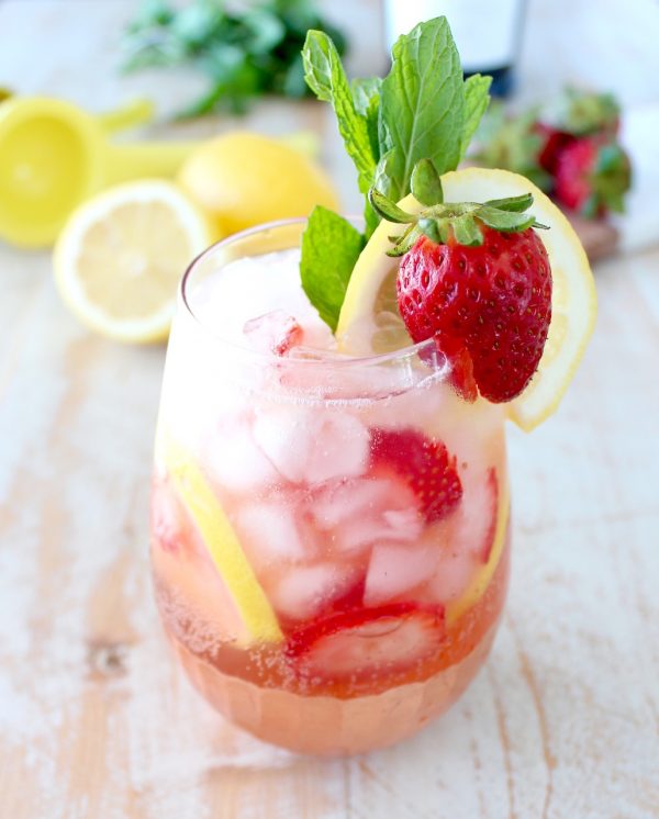 lemon berry prosecco sangria in glass with strawberry, lemon and mint garnish on the side