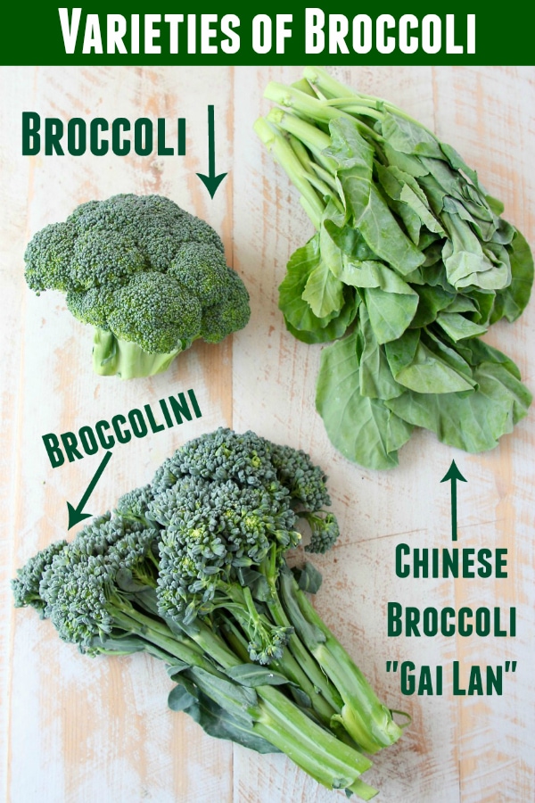 Broccoli, Chinese broccoli and broccolini displayed on white cutting board