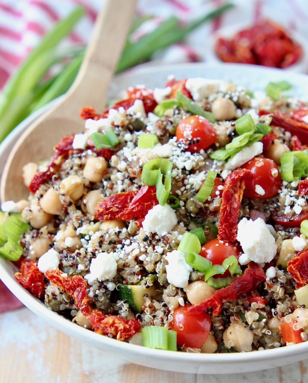 Quinoa salad in bowl with sun dried tomatoes, feta cheese and green onions