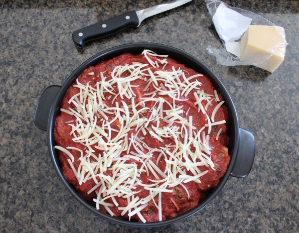 An oven safe pot filled with stuffed shells covered with red sauce and parmesan cheese. 