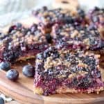 Blueberry oat bars, sliced into squares on a wood cutting board