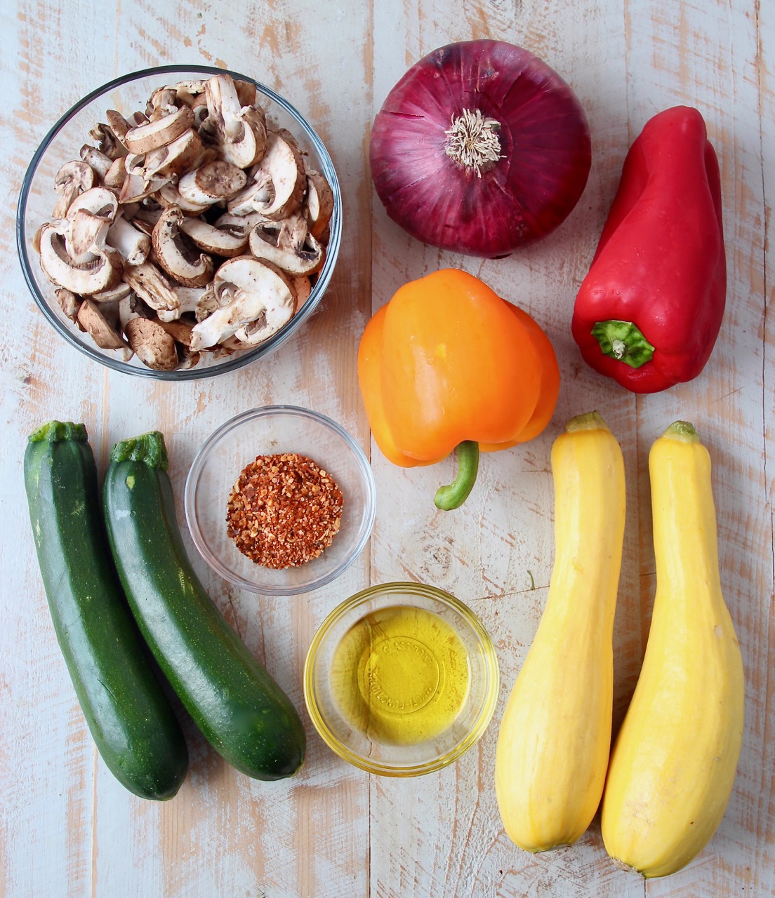 ingredients for grilled vegetable skewers on a white wood board