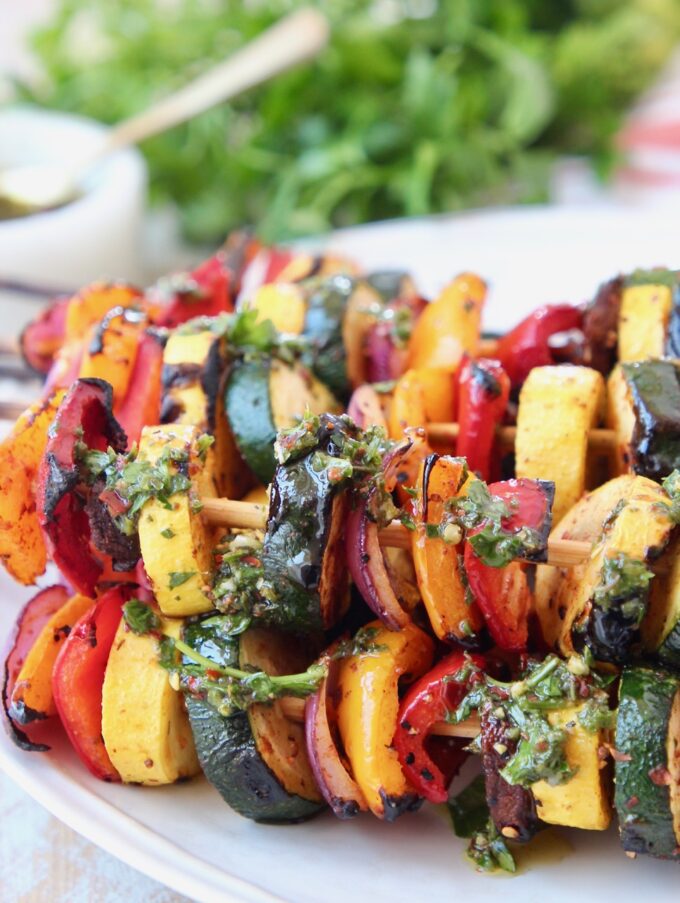 grilled vegetable skewers on plate with chimichurri sauce drizzled on top