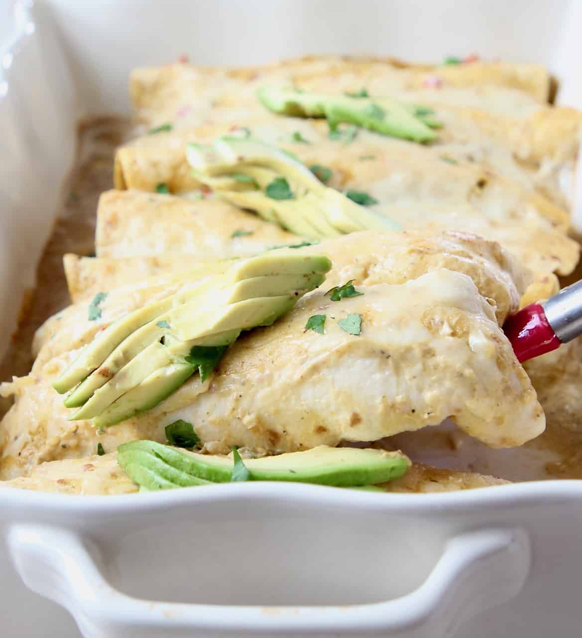 Enchilada lifted out of baking dish with spatula