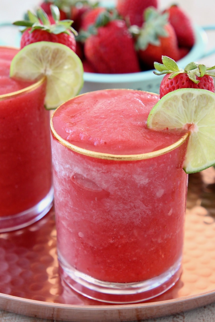 Blended strawberry daiquiri in glass with lime wedge on the side