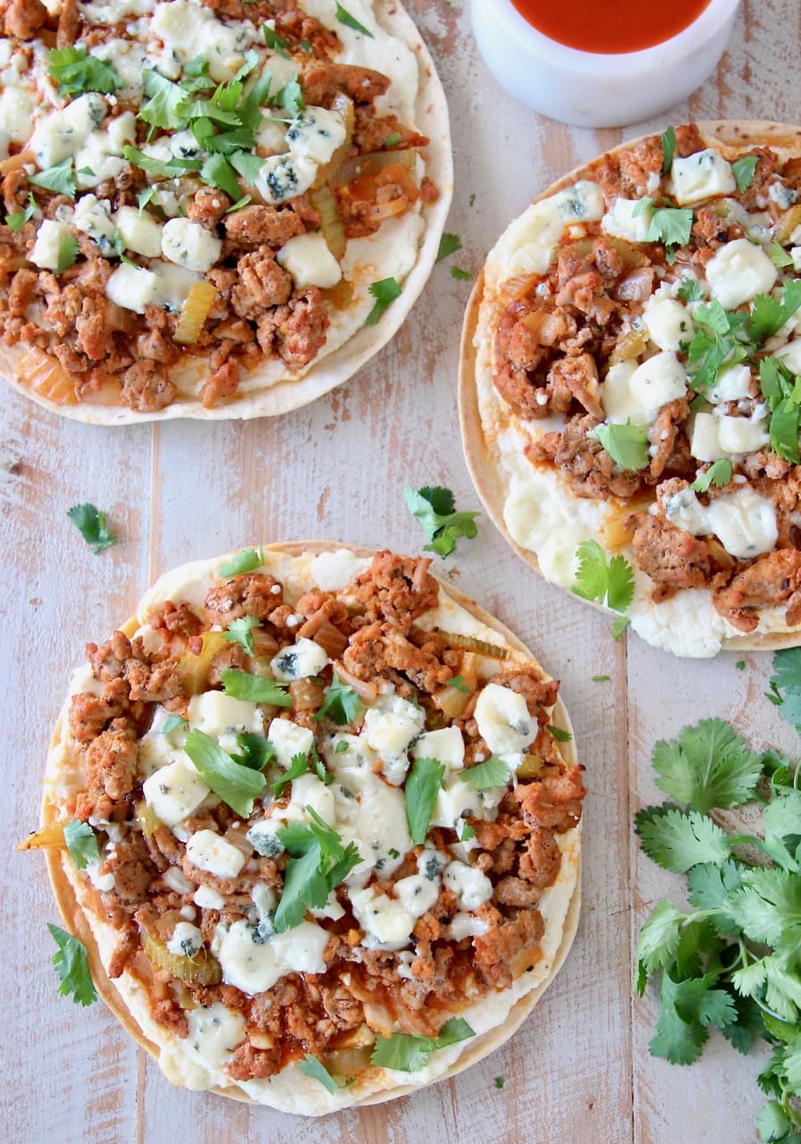 Overhead shot of grilled buffalo turkey flatbread pizzas topped with fresh cilantro