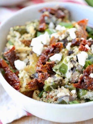 Greek eggs in bowl with feta cheese, sun dried tomatoes and green onions