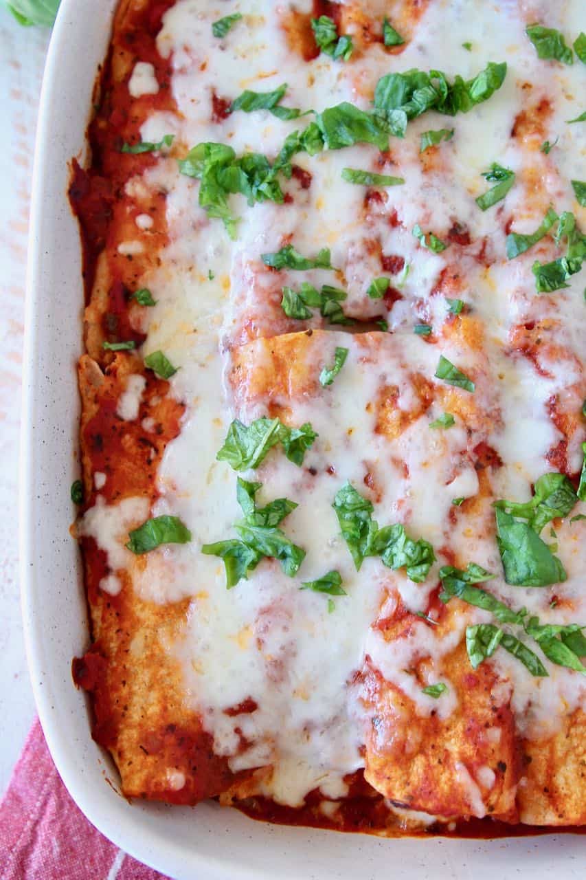 Overhead image of Italian enchiladas in baking dish topped with chopped fresh basil