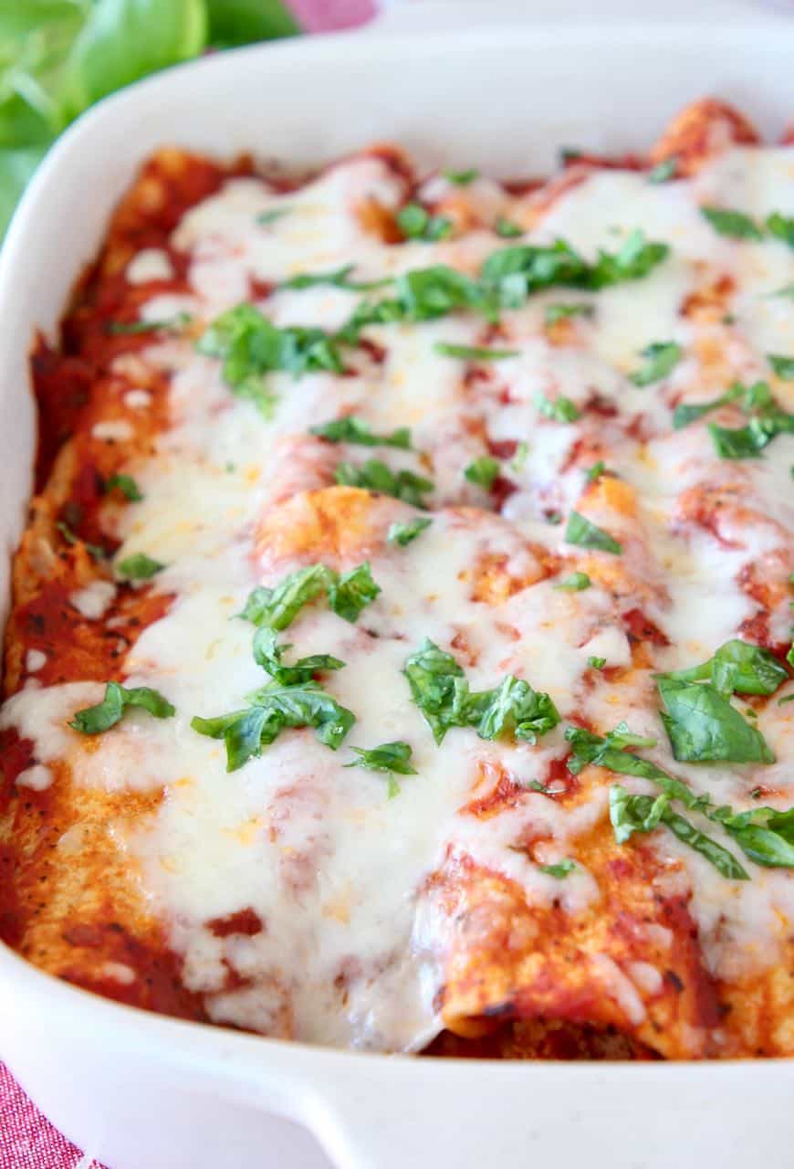 Italian enchiladas covered in melted mozzarella cheese and fresh basil