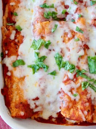 Italian enchiladas in white baking dish topped with fresh basil